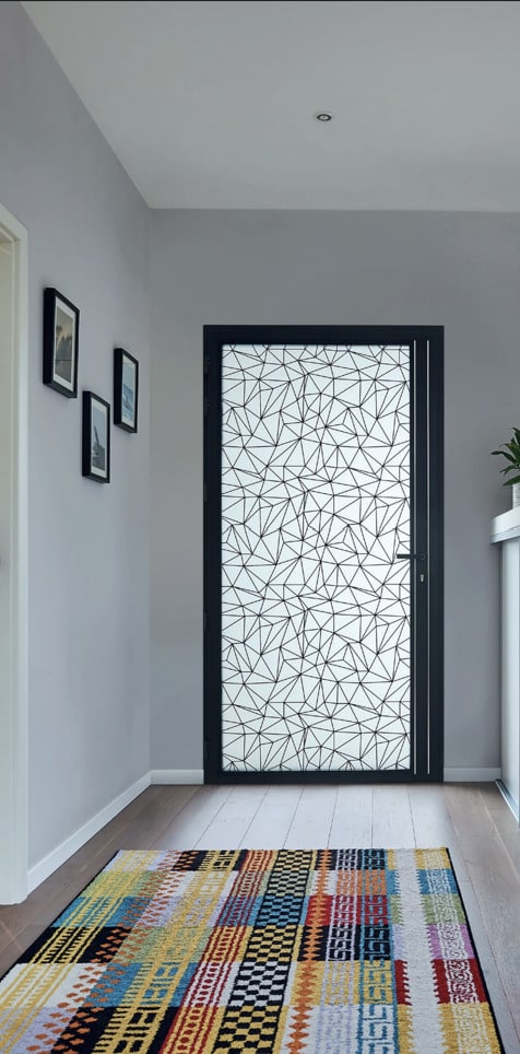 Entrée moderne : porte vitrée avec motif géométrique, tapis multicolore et murs gris épurés.